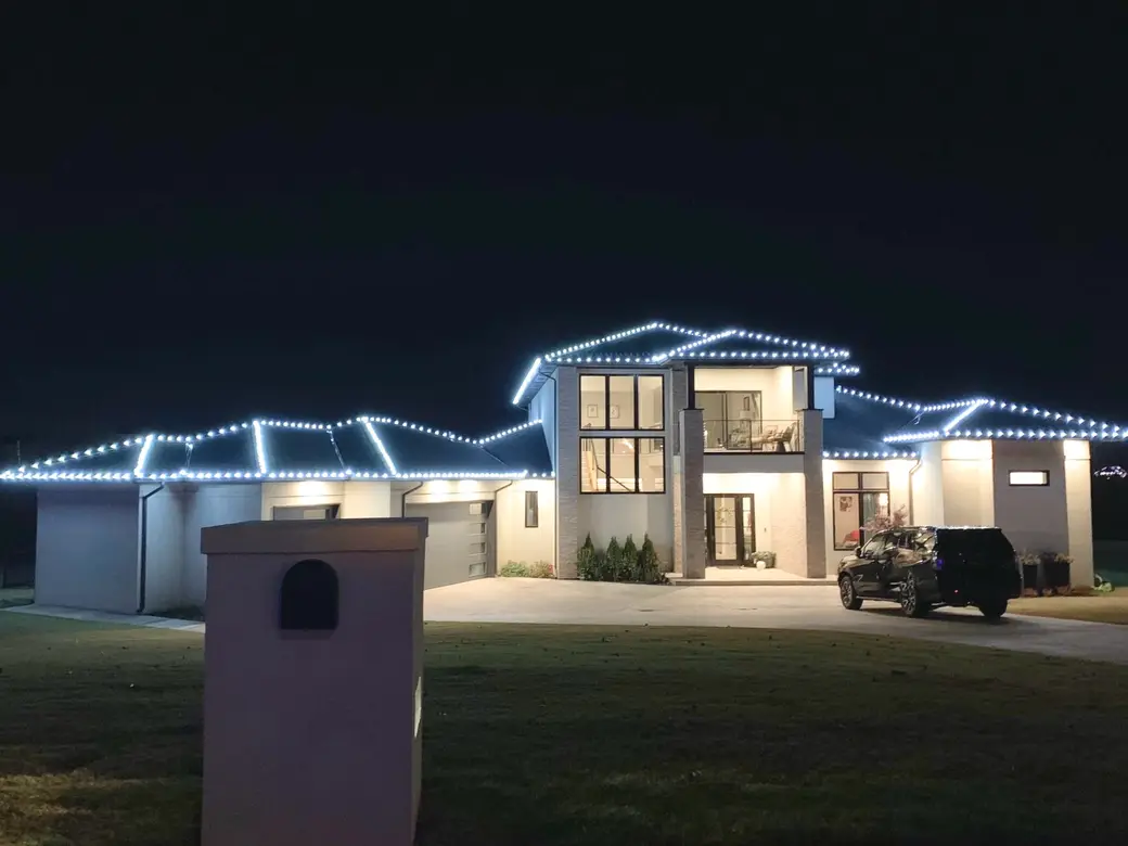 A contemporary two-storey home picked out in cool white bulbs that follow the stepped roofline across the whole frontage.