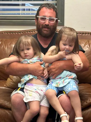 Justin Marks at home on the sofa with his two youngest children.
